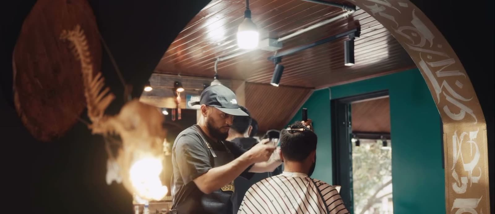 Un barbero trabaja bajo el arco ornamentado del local