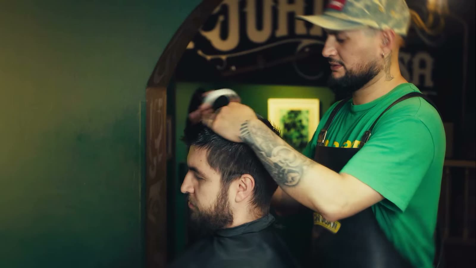 Barbero cortando junto al arco del letrero de madera Don Juan